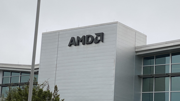 AMD logo on modern corporate building against gray sky.