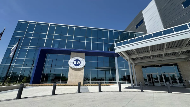 Modern office building exterior with glass facade under clear blue sky.