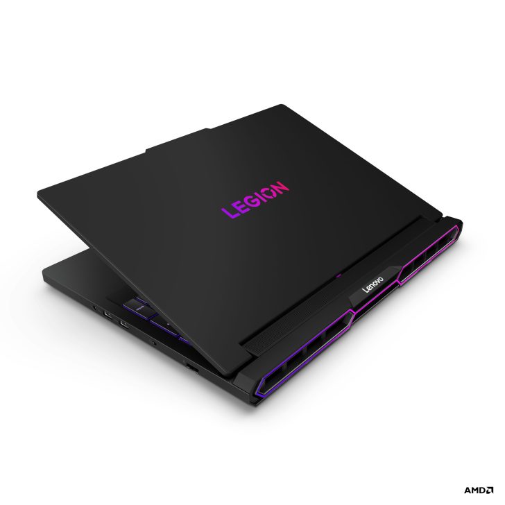 Lenovo Legion laptop with AMD logo partially open, displaying purple lighting and branding on lid and vent, viewed from the back.