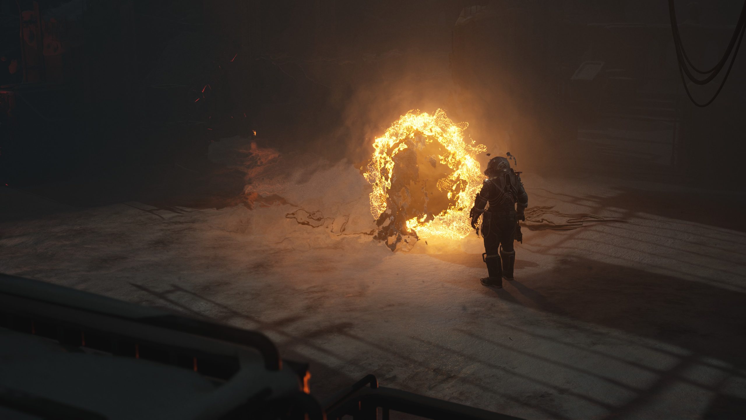 A figure in a dark suit faces a fiery portal in a dimly lit industrial space.