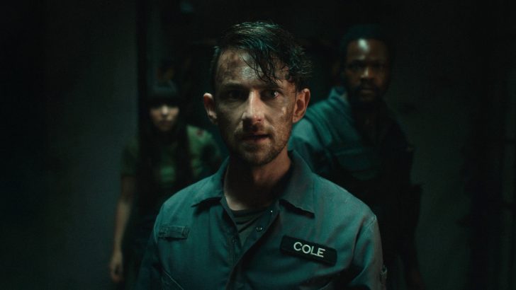 A person in a dark setting wearing a shirt with a name tag that reads COLE.