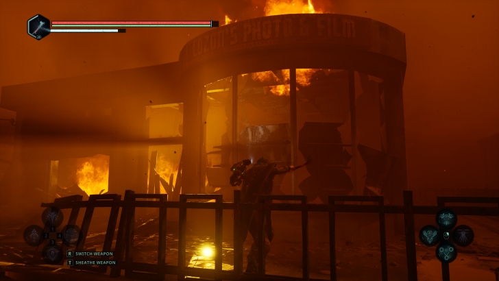 A fiery scene in a game with a character in front of Luzon's Photo & Film, on-screen text Switch Weapon and Sheathe Weapon.