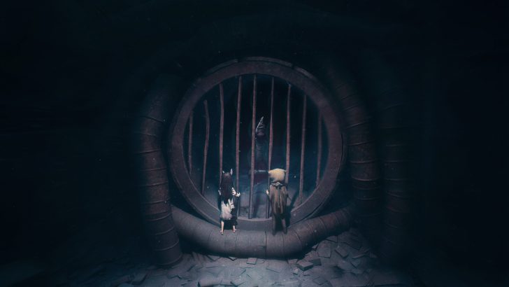 Two characters stand before a barred tunnel entrance with a figure inside reaching out.