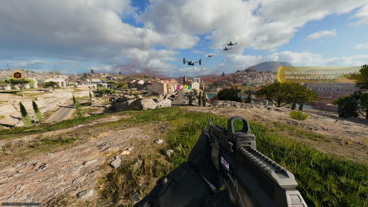 A first-person view in a game showing a rifle aimed at a distant village with on-screen text stating 'Objective is located in a marked area. The search area shrinks as you approach your target.'