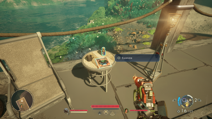 In a gaming scene, a player stands on a balcony overlooking a river, aiming a weapon at a round table with a magazine and a bottle, with the option to 'Examine' displayed on screen.