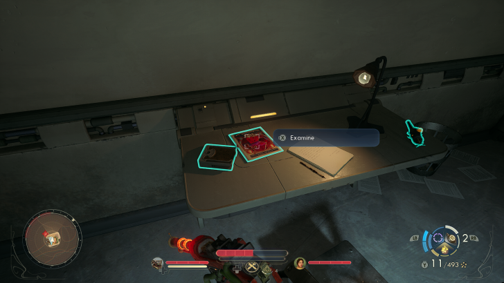 A desk in a game contains a red magazine and other items with a prompt to 'Examine' them, alongside a circular mini-map and character status indicators in the UI.