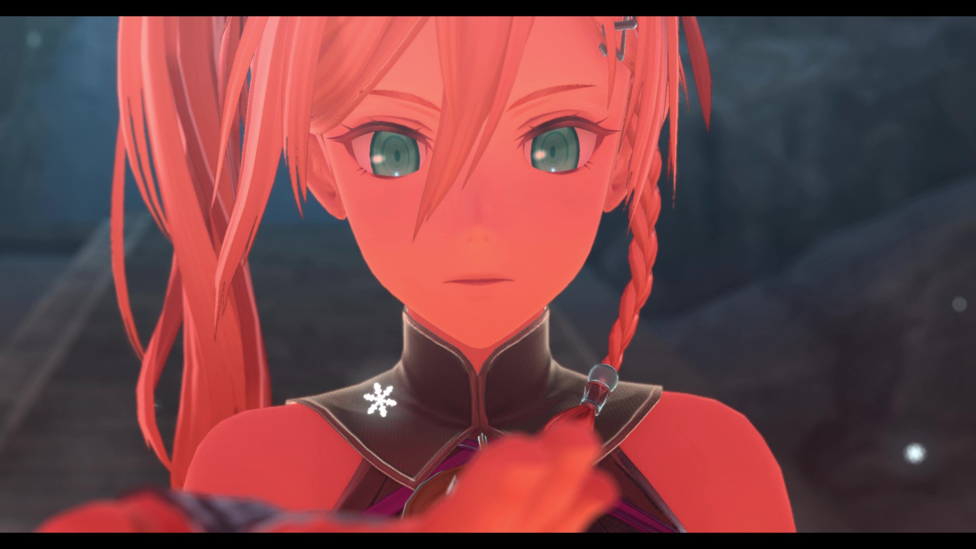 A close-up of a female character with red hair and glowing green eyes from the game Bandai Namco's Tales of Arise, holding a glowing object.