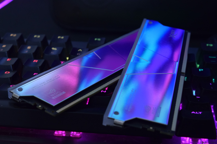 Two ASUS ROG DDR5 memory modules with RGB lighting rest on a keyboard with illuminated keys.