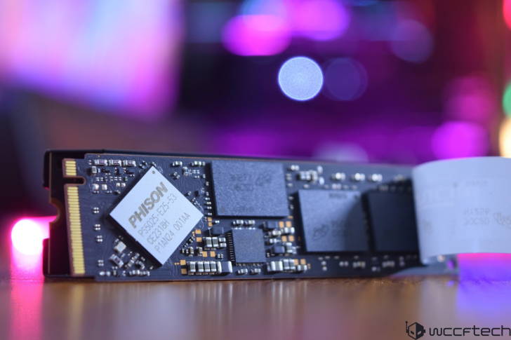 A close-up of a Phison PS5025-E25-53 solid-state drive against a blurred, colorful background.