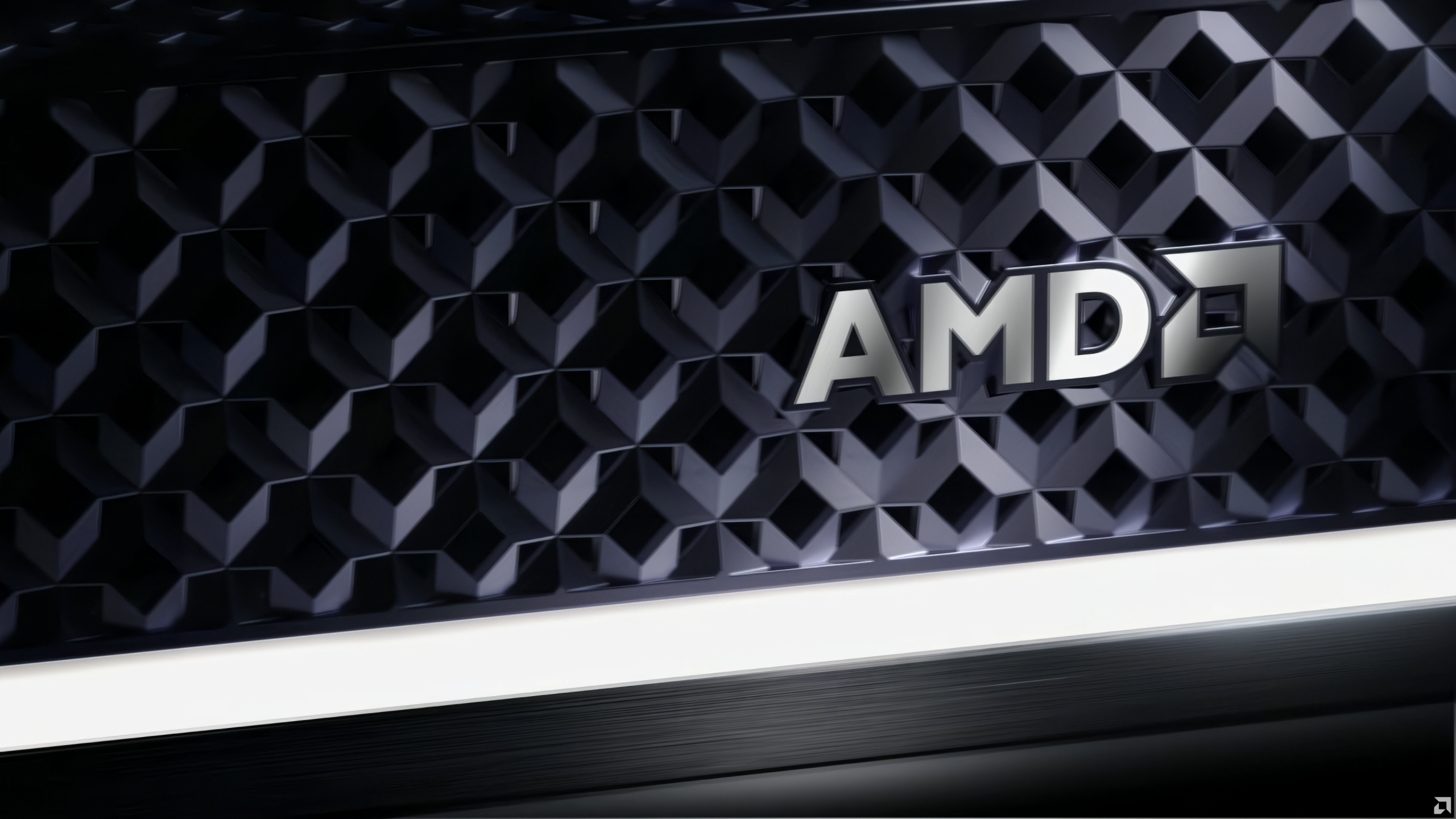 A close-up of a dark patterned surface featuring the silver AMD logo in the center.