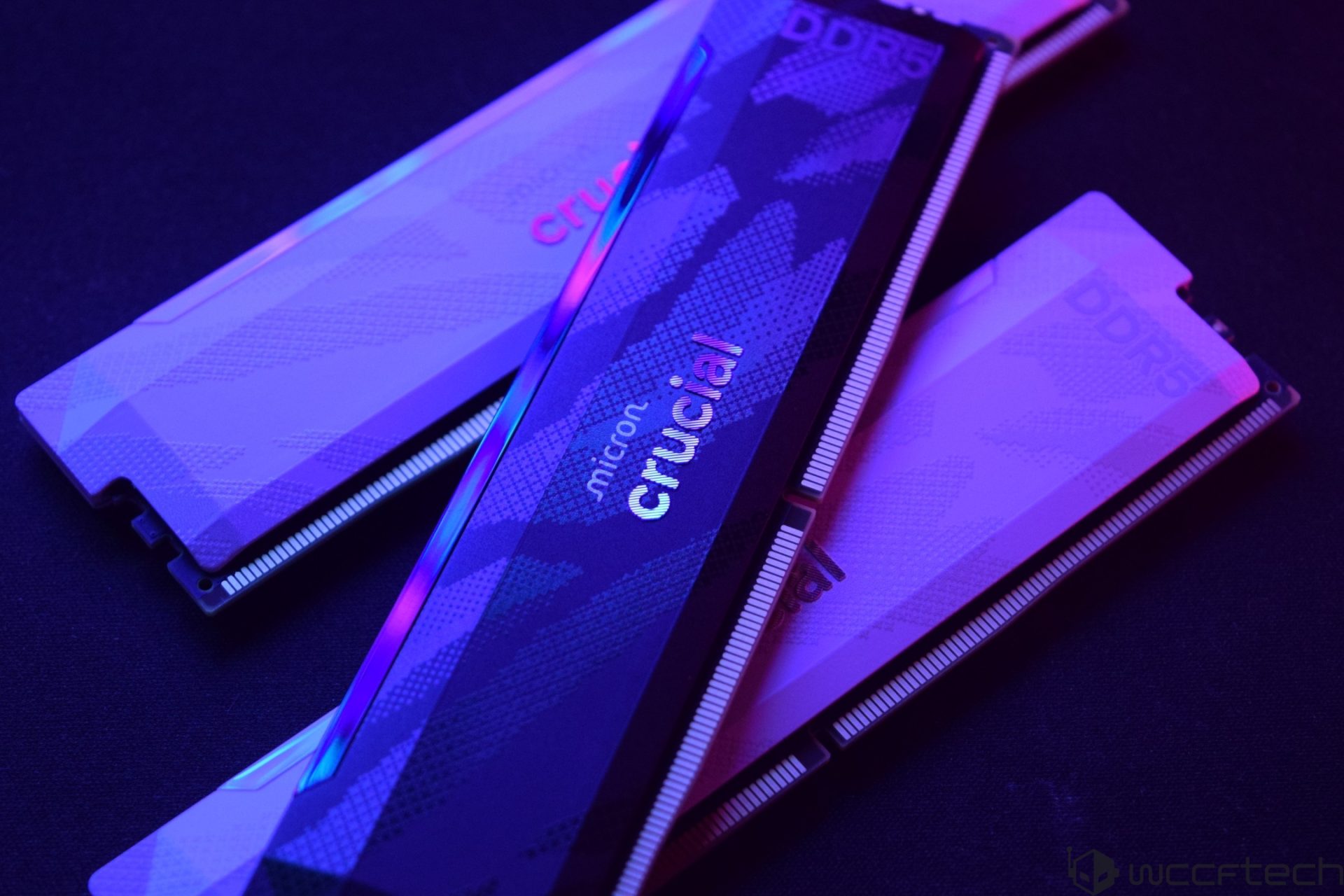 Three Crucial DDR5 RAM sticks with 'micron' branding are illuminated in purple and blue lighting.