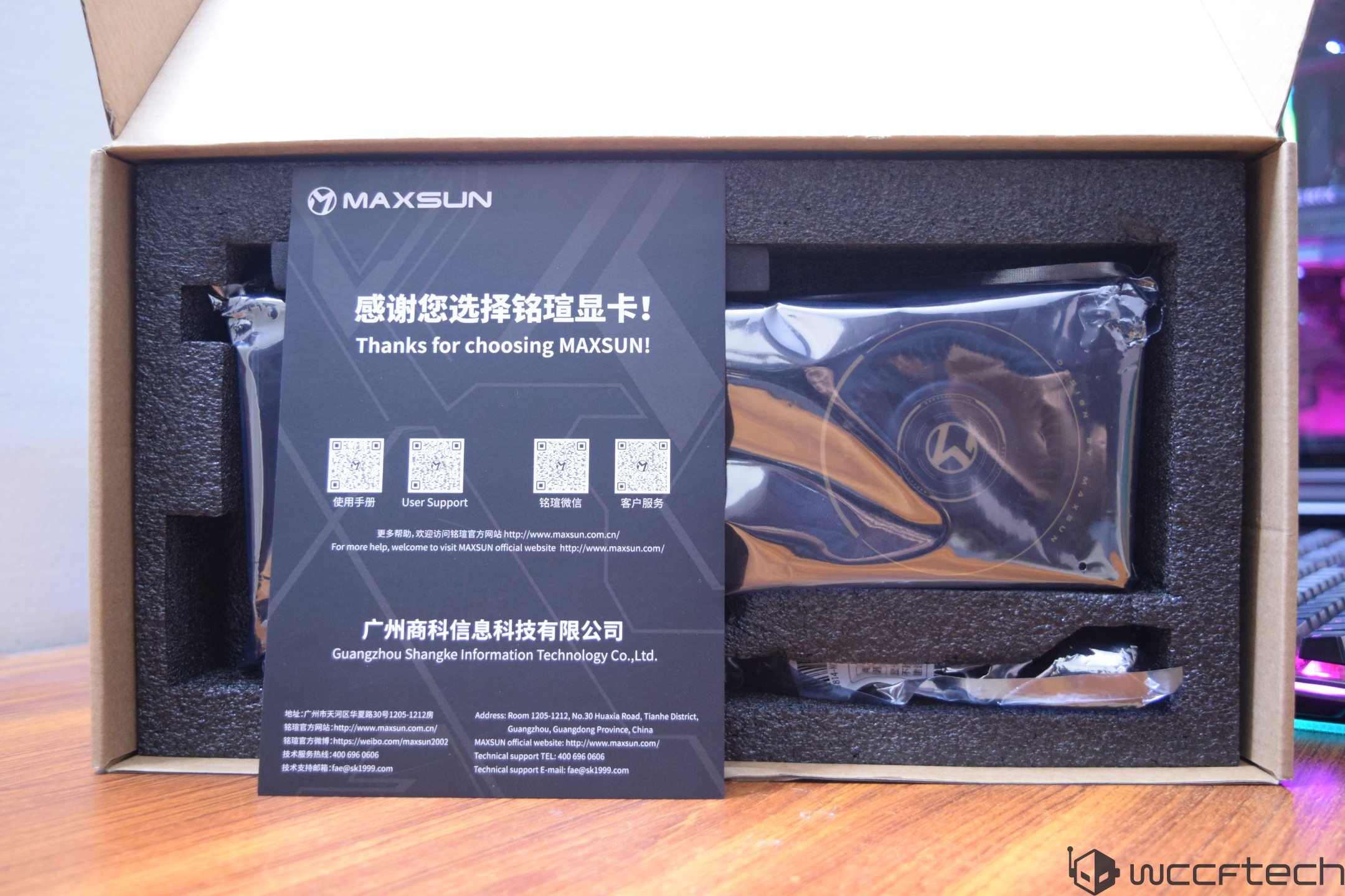 The image shows a MAXSUN graphics card in its packaging, accompanied by a card with text saying 'Thanks for choosing MAXSUN,' with QR codes for user support and additional information.