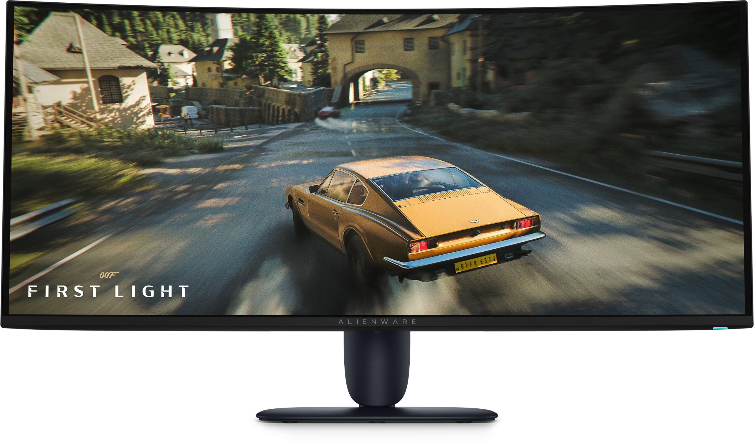 An Alienware monitor displays a scene from the game 'First Light' featuring a yellow classic car driving through a scenic town.