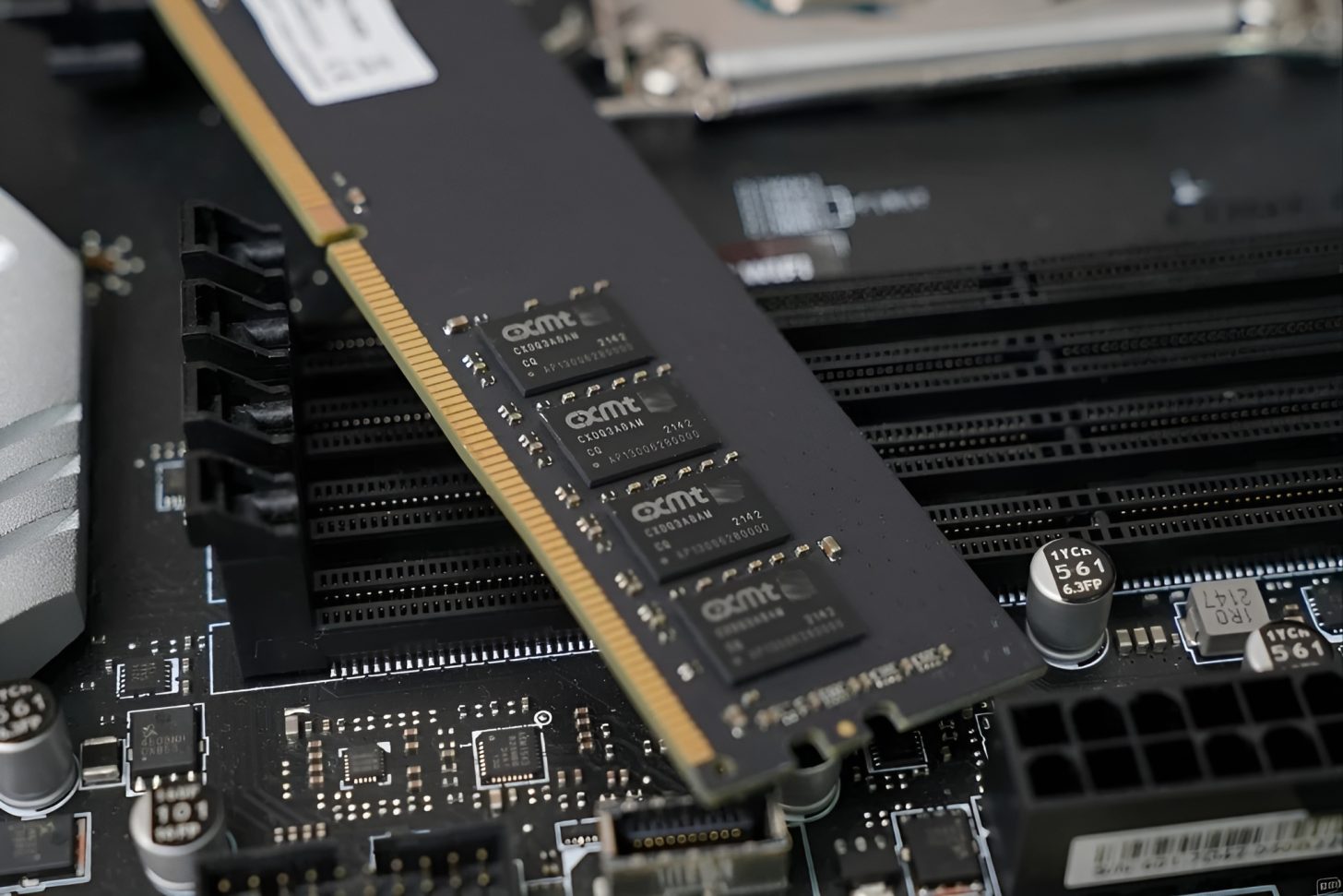 A close-up of an unbranded RAM module with 'cxmt' chips partially inserted into a motherboard slot.