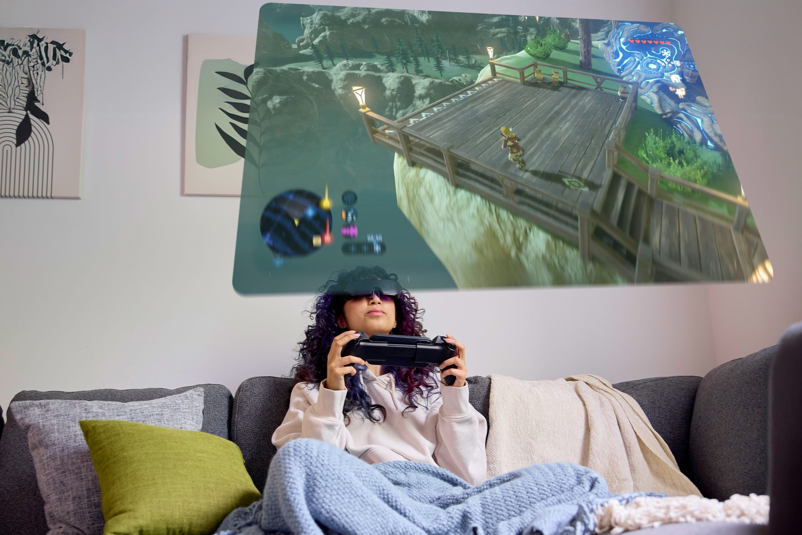 A person wearing VR goggles, using a handheld controller, plays a game projected above them on a holographic screen.