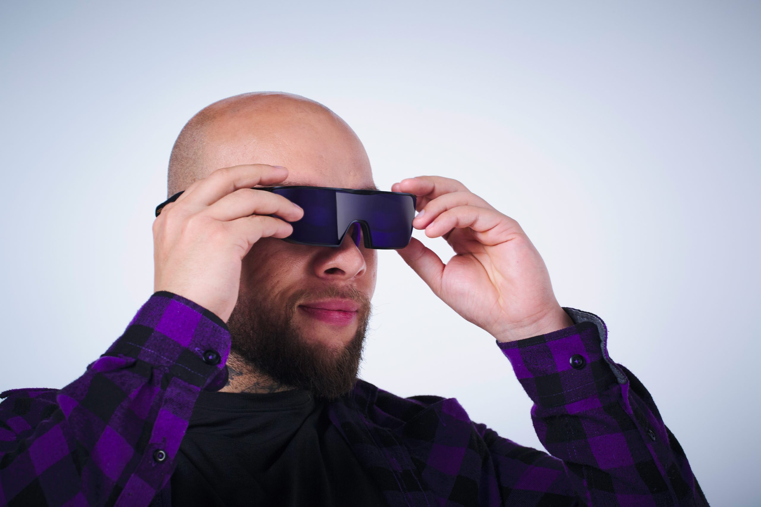 A person wearing dark virtual reality glasses while adjusting them with both hands.