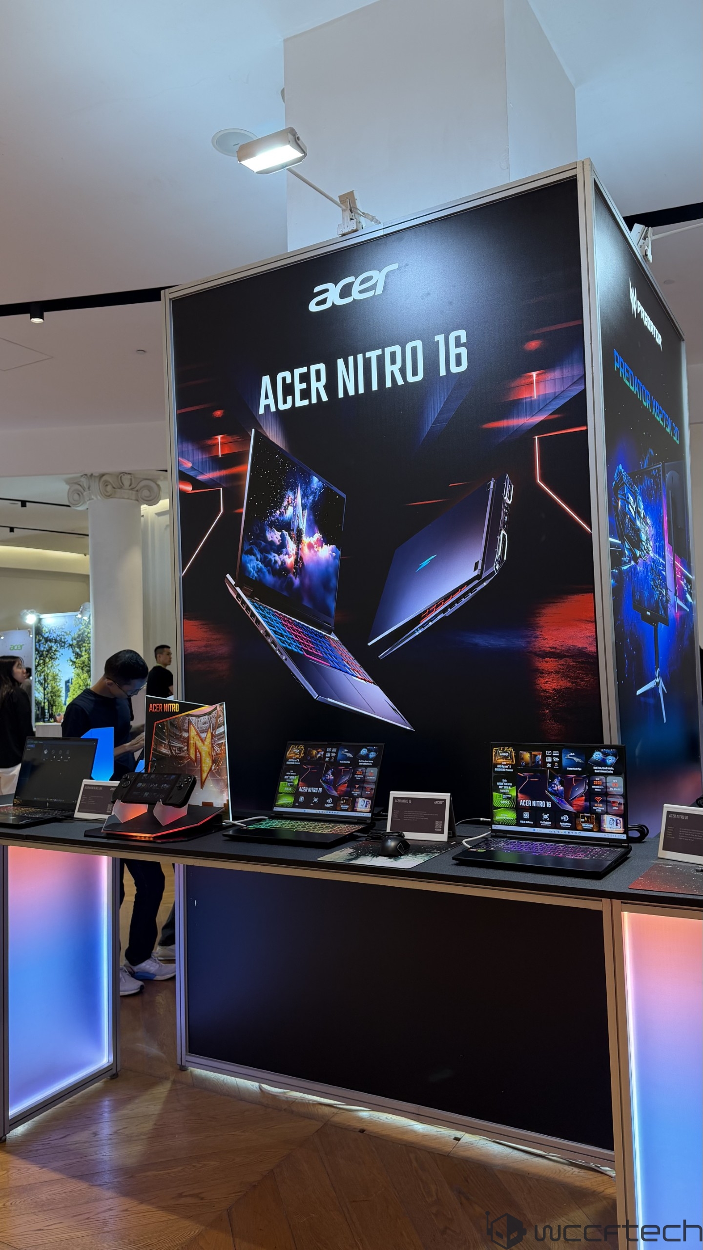 Display of Acer Nitro 16 laptops with a prominent sign 'ACER NITRO 16' and various models showcased on a table.