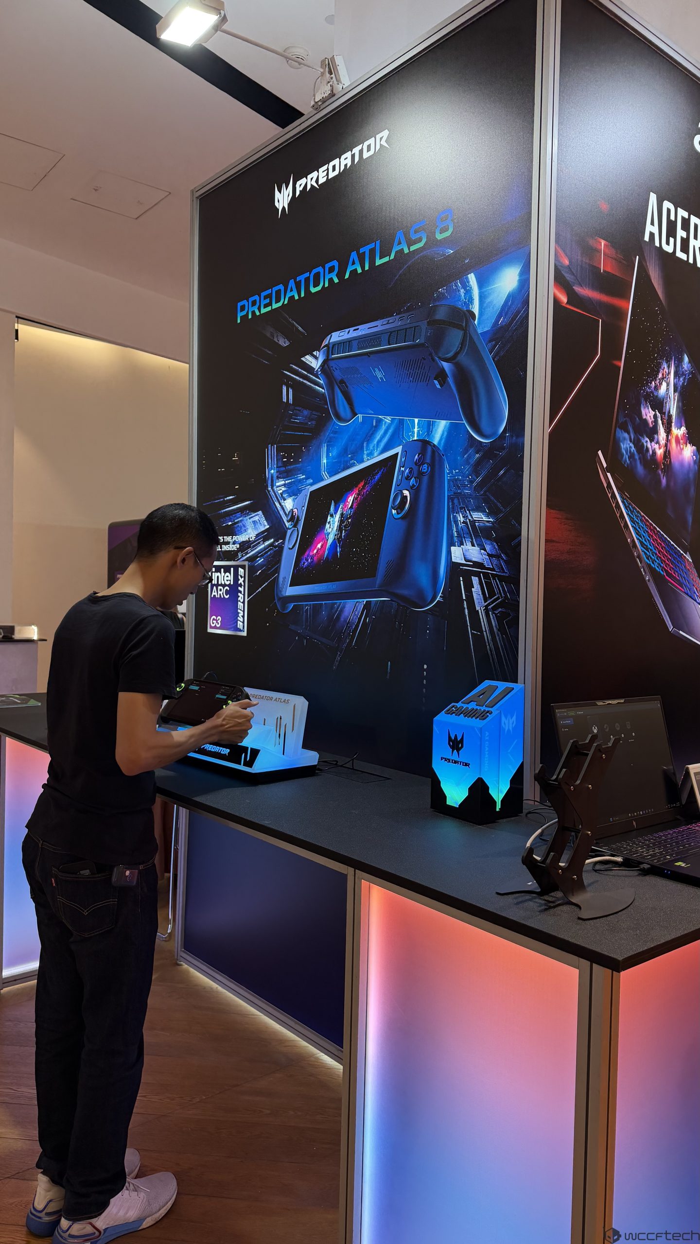 A person interacts with an Acer Predator Atlas 8 handheld gaming device at a display featuring 'Intel Arc Extreme' branding.