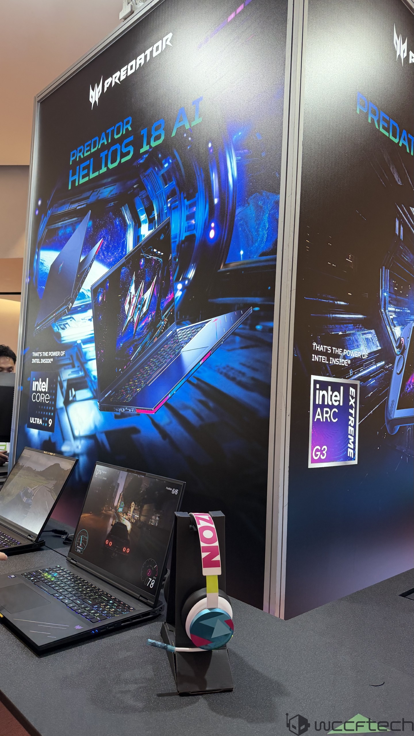 A display showcases the Acer Predator Helios 18 AI laptop featuring an 'Intel Core Ultra 9' processor and an 'Intel ARC Extreme G3' graphics card, with nearby headphones and a gaming demo running on the laptop screen.