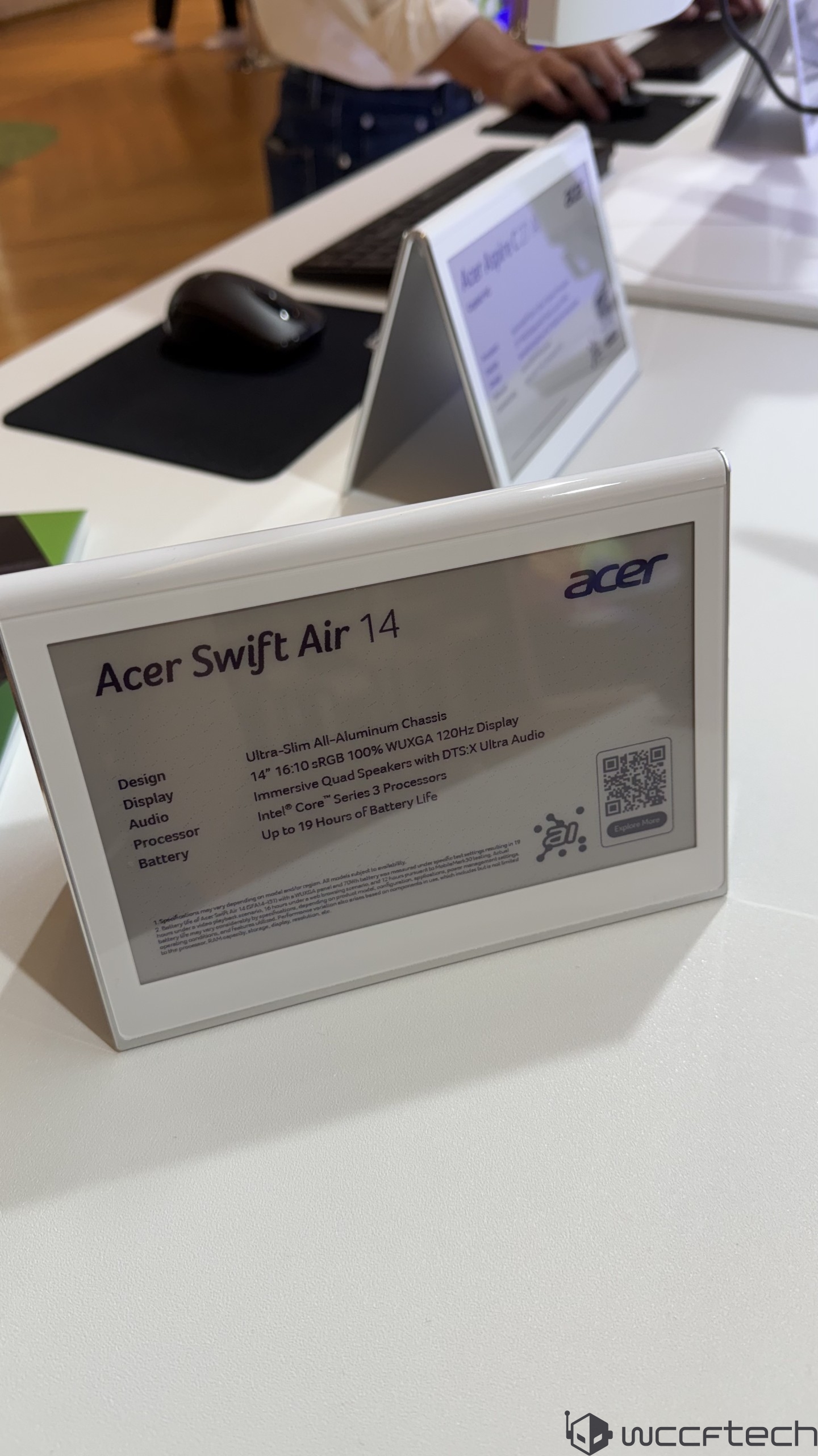 A close-up of a promotional card detailing the Acer Swift Air 14, featuring a 14 16:10 RGB WUXGA 120Hz display and Intel Core Series 3 processors, with a promise of up to 19 hours of battery life.
