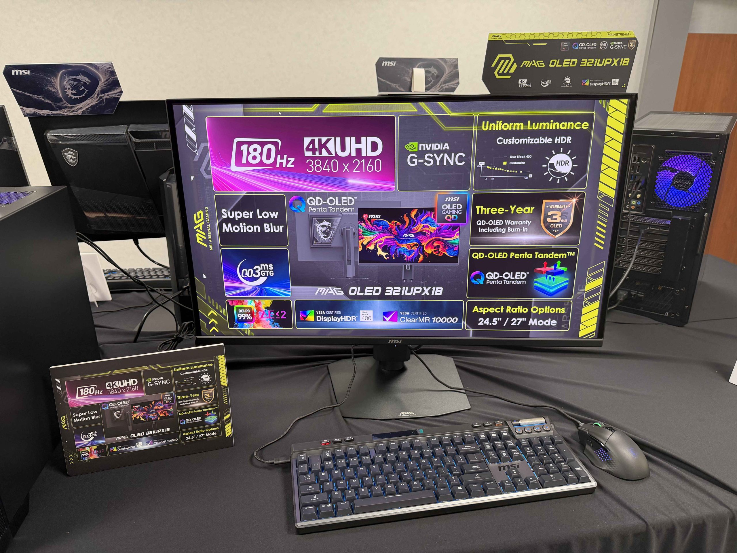 An MSI MAG OLED 32UPX18 monitor displaying features such as '4KUHD 3840 x 2160,' '180Hz,' NVIDIA G-SYNC, and 'QD-OLED Penta Tandem.'