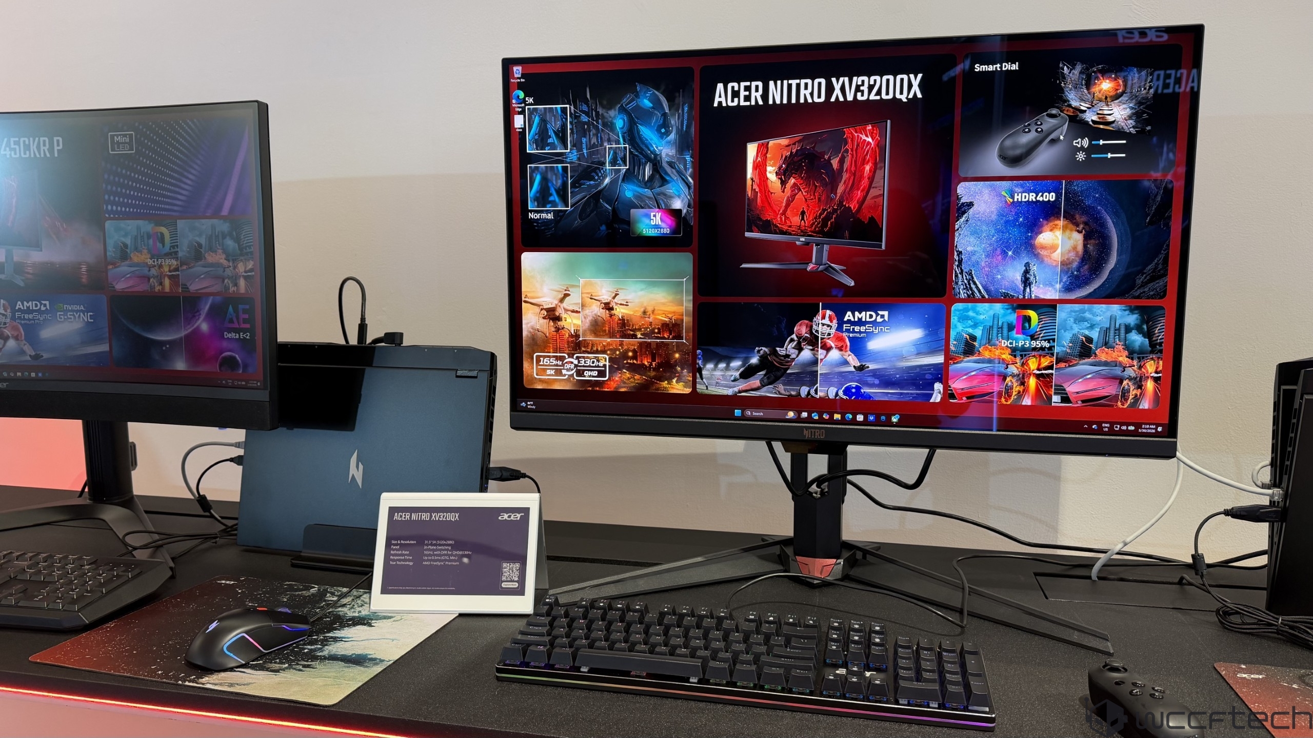 The image features an Acer Nitro XV320QX monitor displaying its features, including '165Hz,' '330 nits,' 'QHD,' 'HDR400,' and support for AMD FreeSync, alongside a keyboard and mouse on a desk.