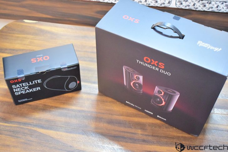 OXS Satellite Neck Speaker and Thunder Duo speaker system packaging on a wooden surface.