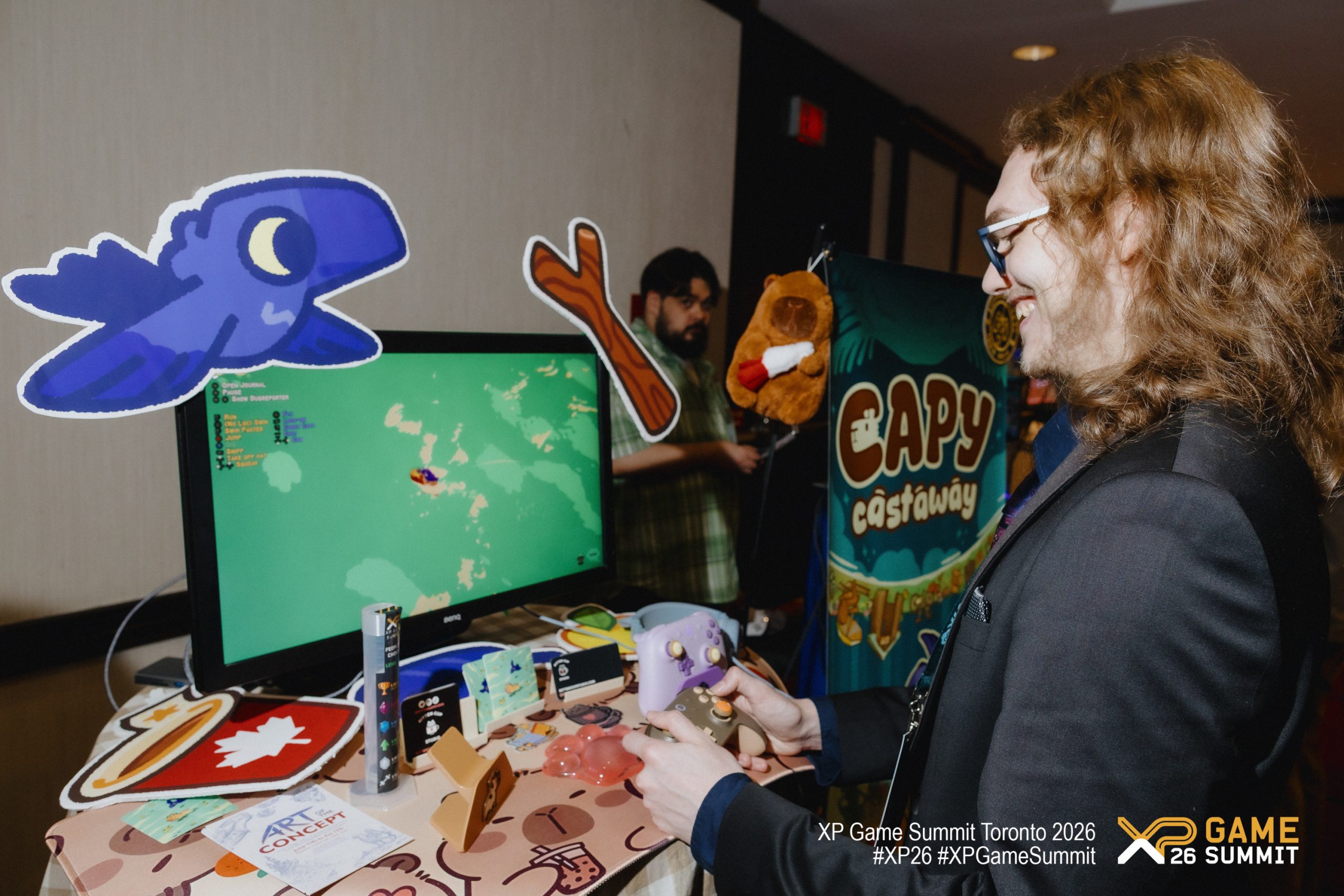A person is holding a controller and playing a video game titled Capy Castaway on a monitor during the XP Game Summit Toronto 2026.