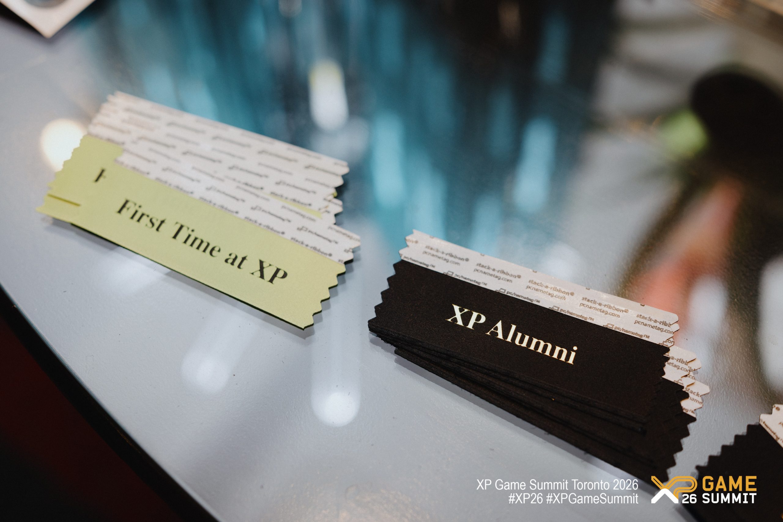Name tags with the text 'First Time at XP' and 'XP Alumni' are displayed at the XP Game Summit Toronto 2026.