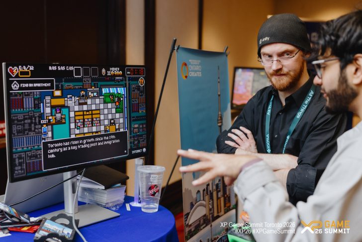A person wearing a Unity hat stands next to another individual, both observing a pixelated city-building game on a monitor displaying a message about Toronto's growth.