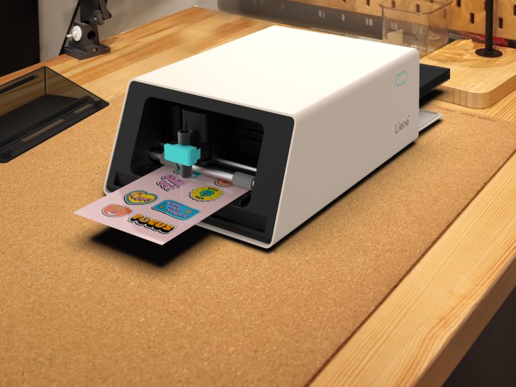 A Liene printer on a wooden desk is printing colorful stickers with various designs and texts like Focus and Chill Out!