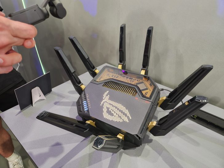 An ASUS ROG gaming router with multiple antennas displayed on a table, featuring an illuminated ROG logo and '6G' text.