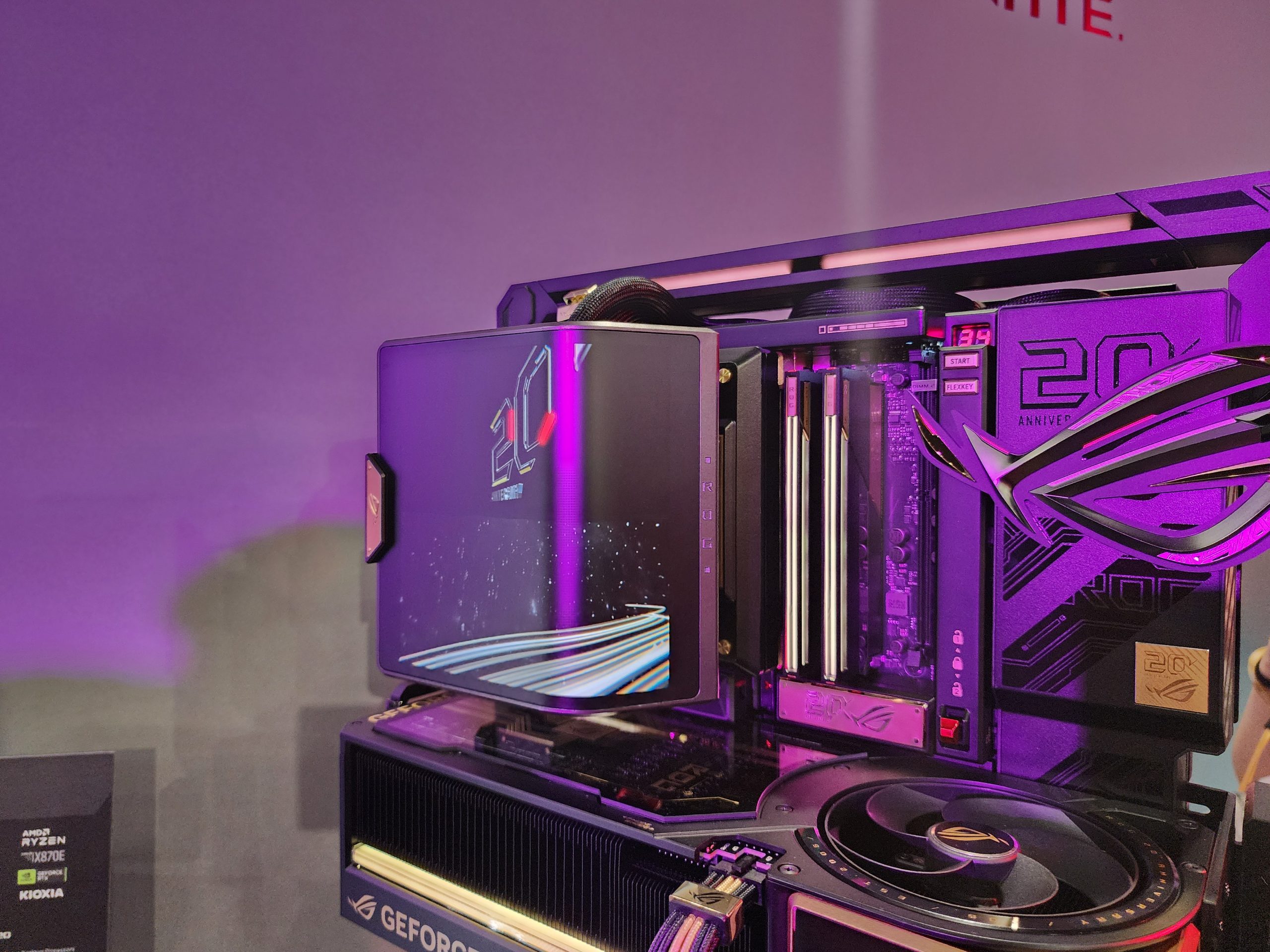 An ASUS Republic of Gamers 20th Anniversary Edition PC build, featuring a visible 'GEFORCE RTX' graphics card and the 'ROG 20 YEARS' logo illuminated in a purple-lit setup.