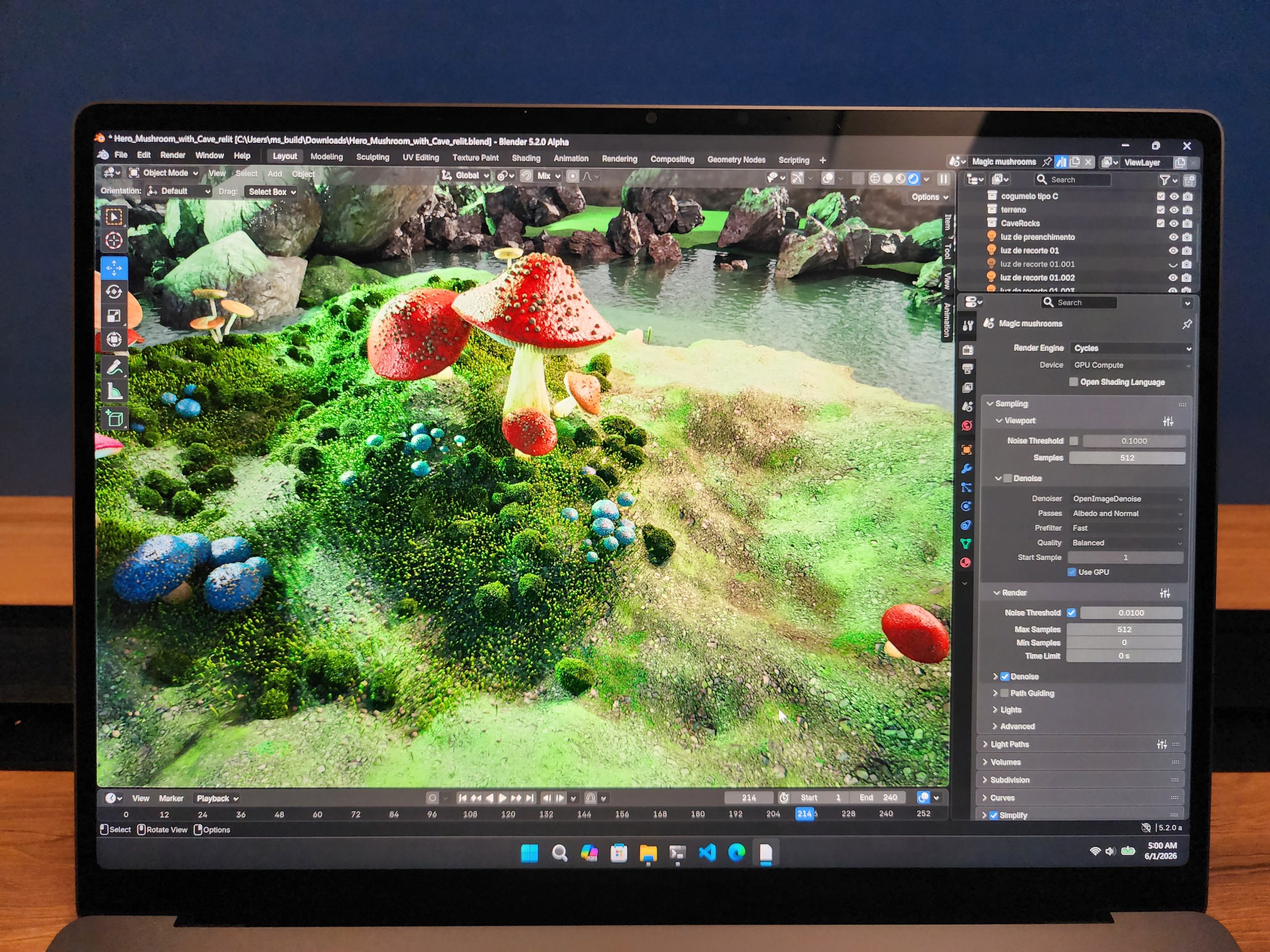 A laptop screen displays a 3D rendering of colorful mushrooms in a natural setting using Blender 5.2.0 Alpha.
