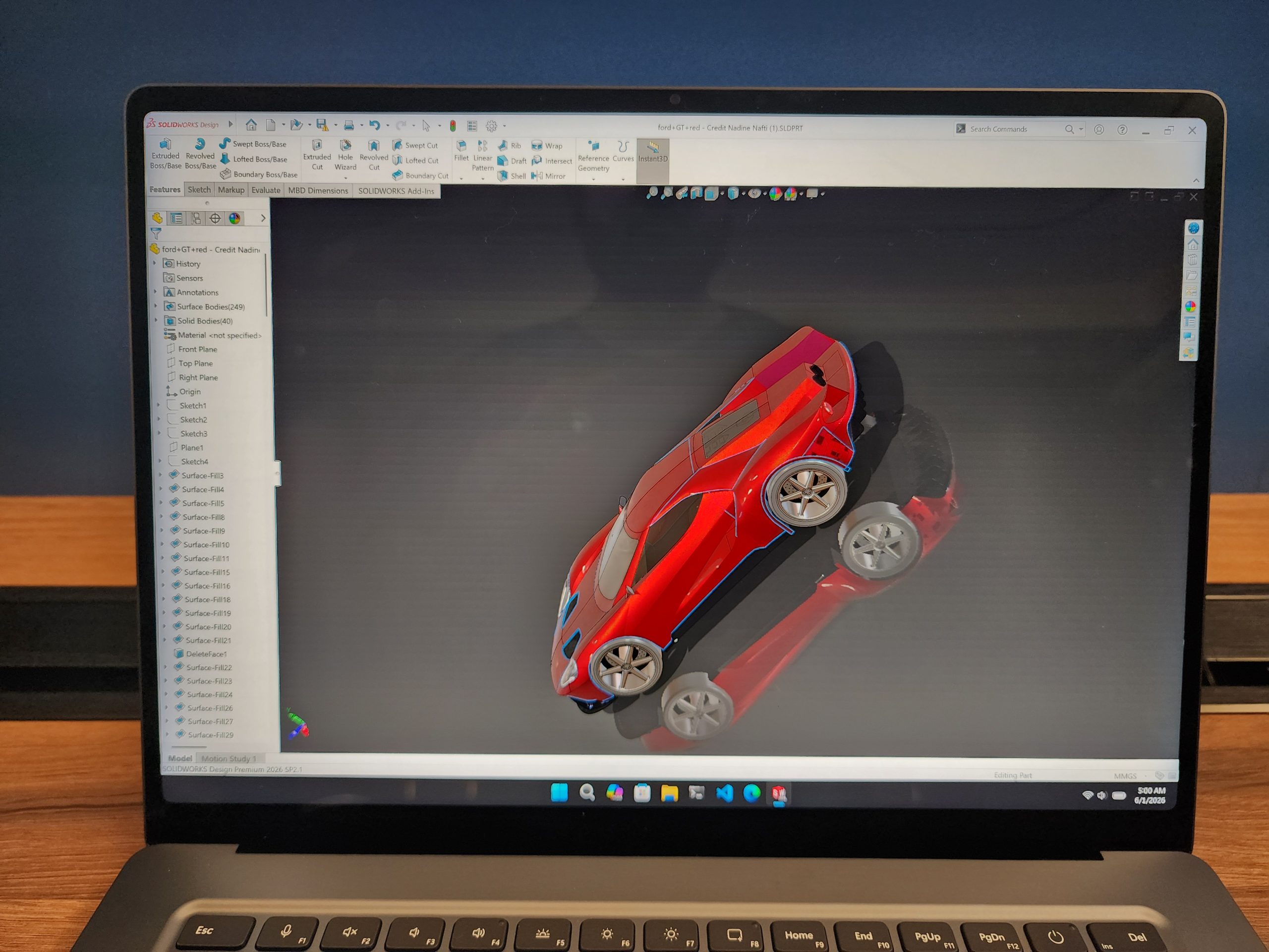 A laptop screen displaying a 3D model of a red car in SOLIDWORKS Design Premium 2020 SP5.1 software.