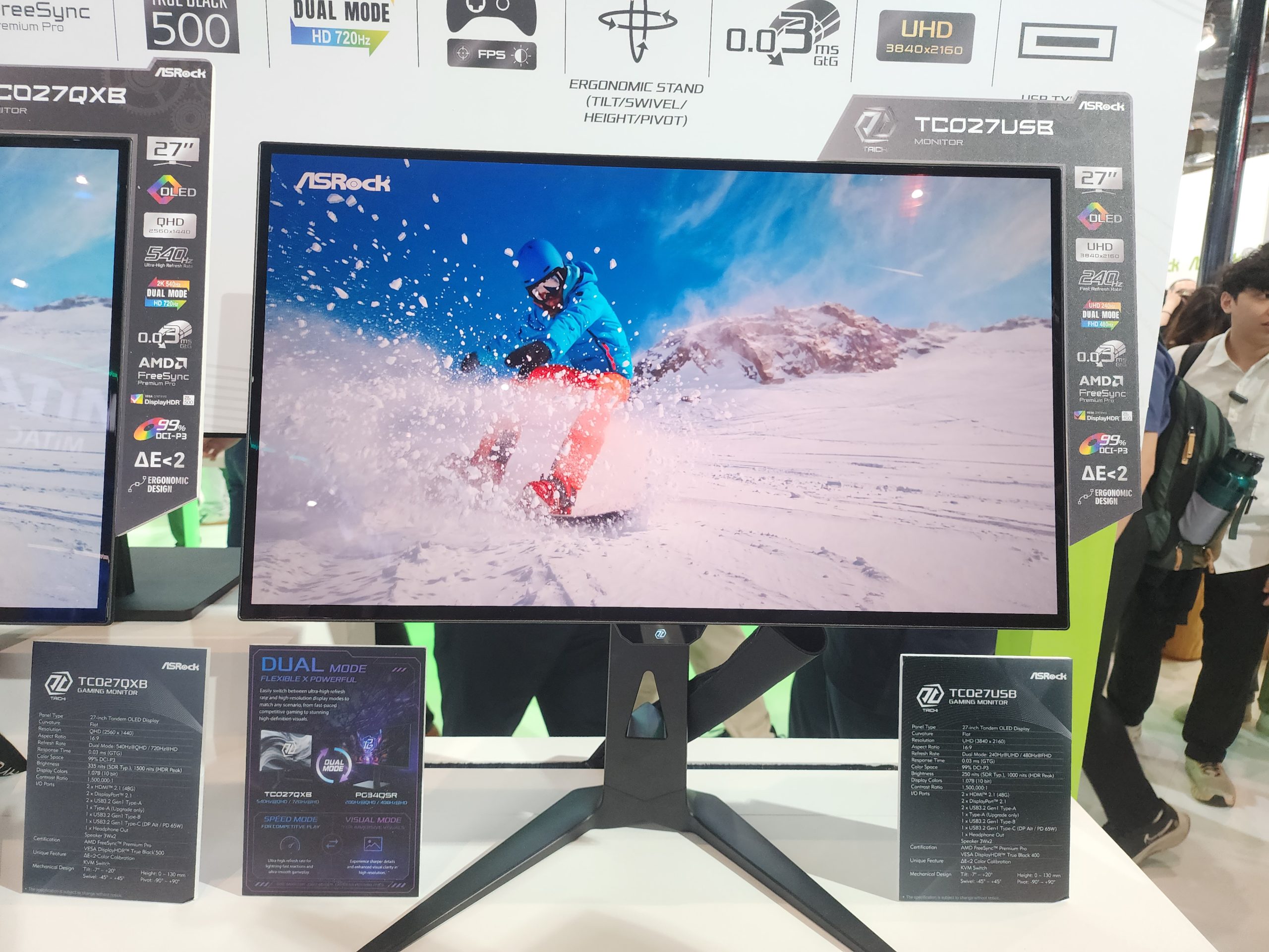 An ASRock TCO27USB monitor, displaying a snowboarding scene, features a 27 OLED screen with UHD 3840x2160 resolution and AMD FreeSync technology.