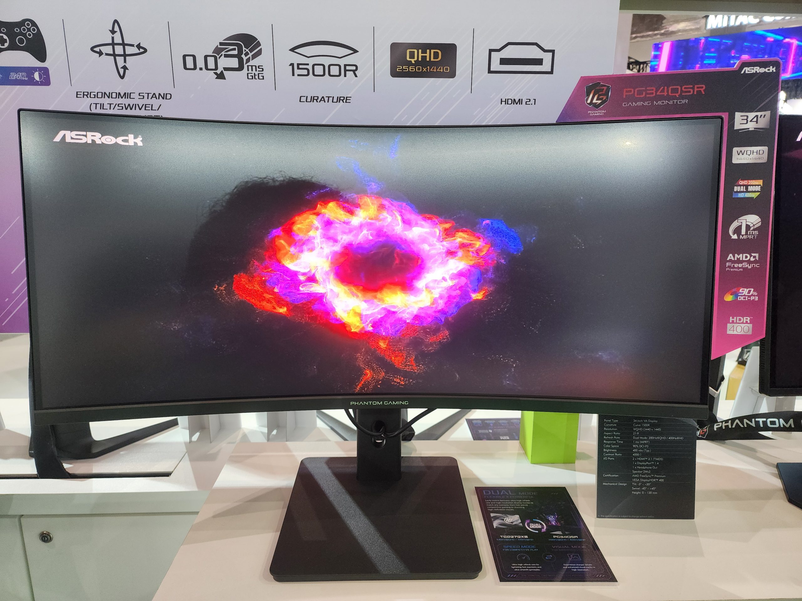 The ASRock PG34QSR 34 gaming monitor is displayed with a vibrant image on-screen, featuring QHD resolution of 2560x1440, 0.03 ms GTG response time, 1500R curvature, AMD FreeSync, and HDR 400 support.