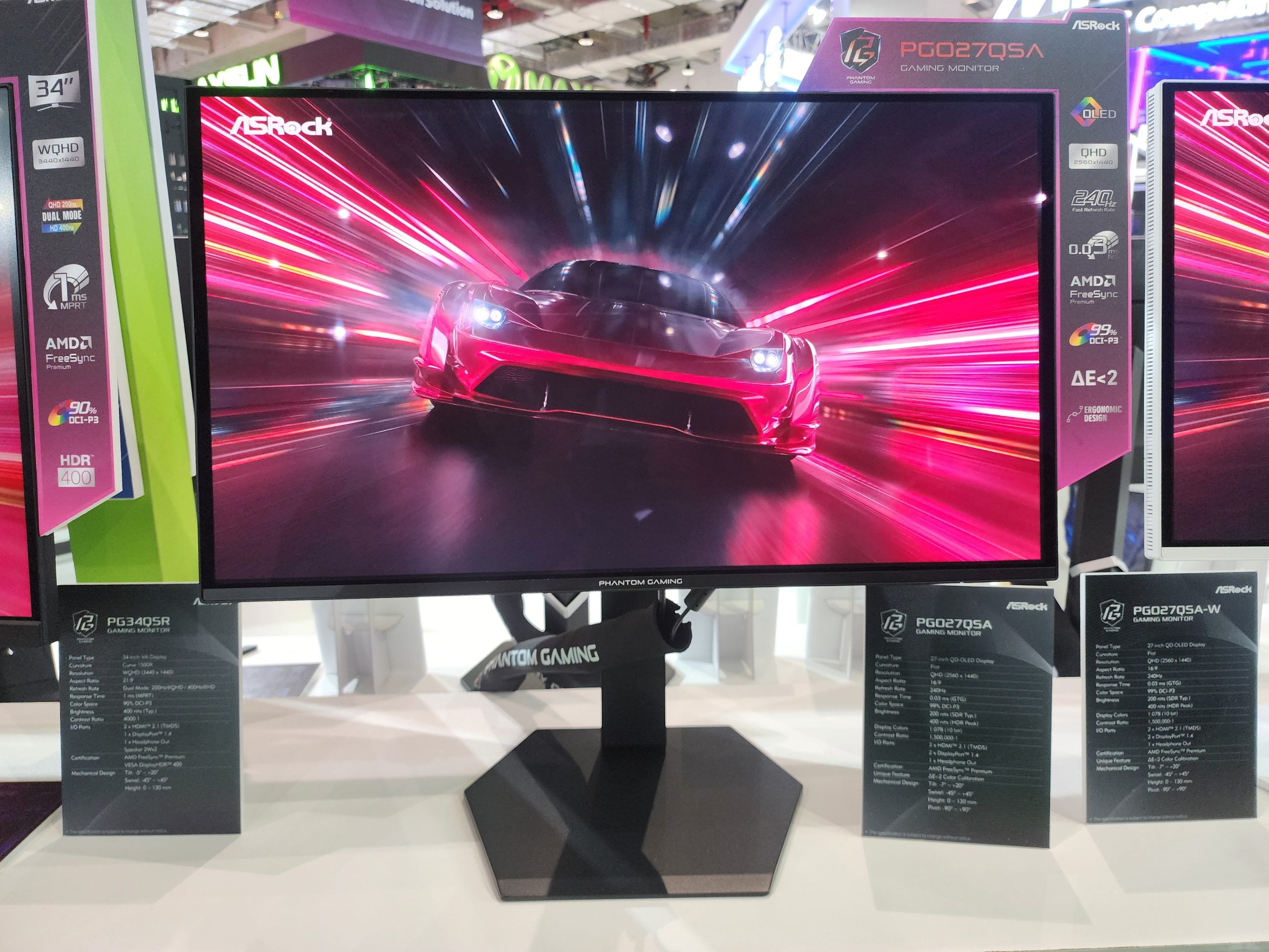 The ASRock PGQ2705A gaming monitor is displayed showing a high-speed car scene on its screen, with features like OLED, 240 Hz, and AMD FreeSync highlighted.