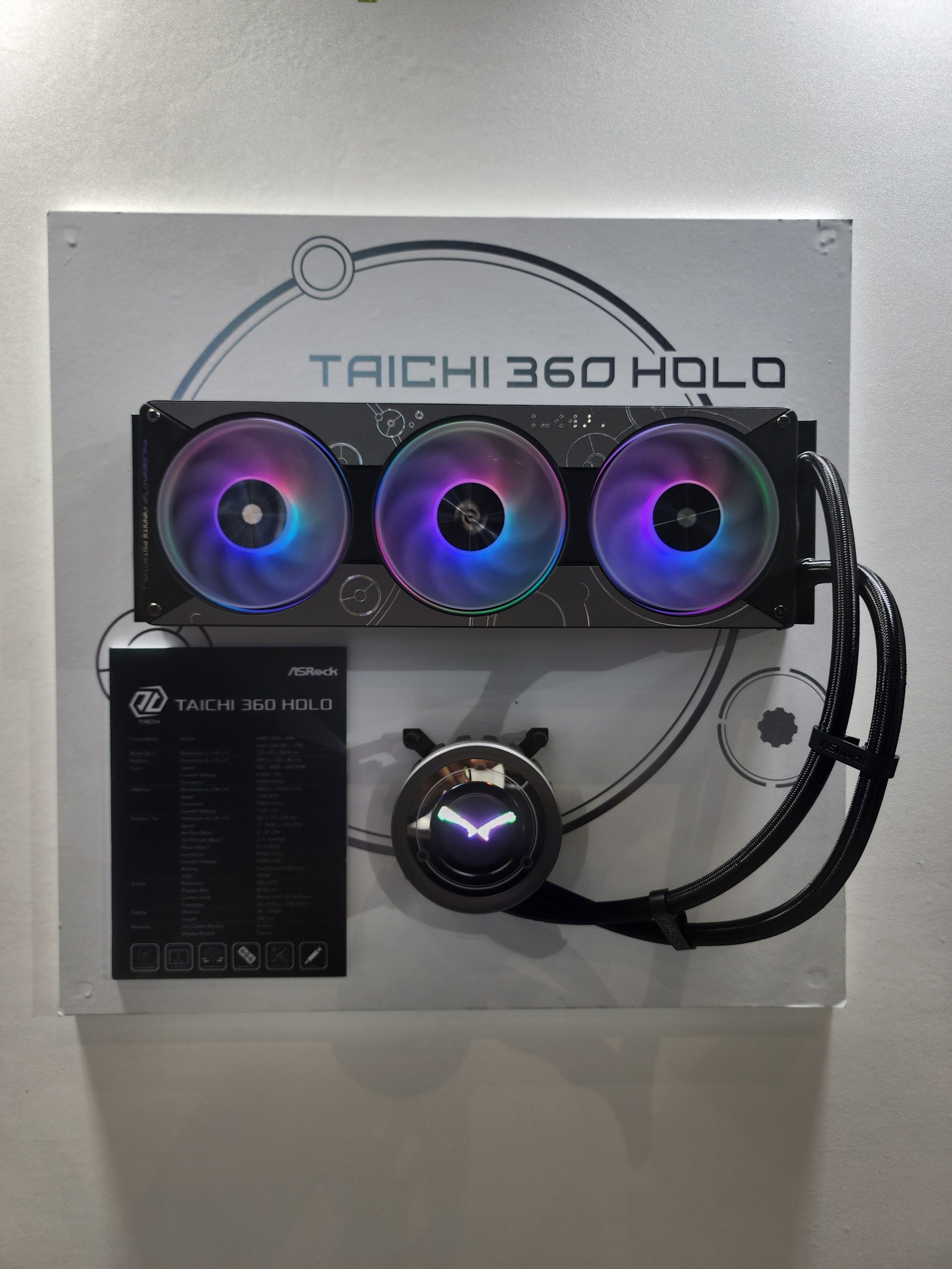 An ASRock Taichi 360 Holo CPU cooler with three RGB fans and an illuminated pump is displayed against a background featuring the 'Taichi 360 Holo' branding.