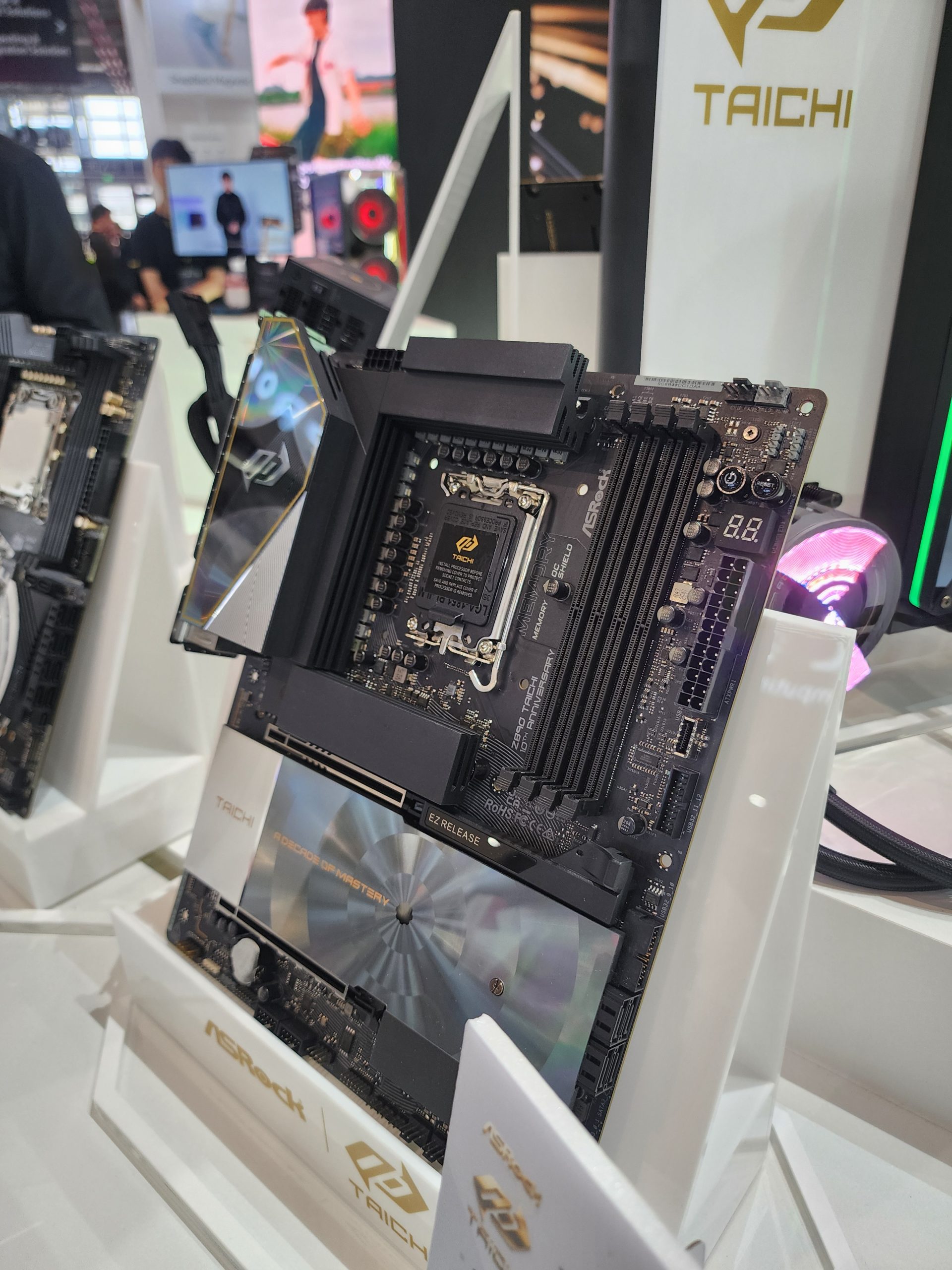 An ASRock Taichi series motherboard is displayed vertically, featuring branding and the text 'ROCK OF MASTERPIECE.'