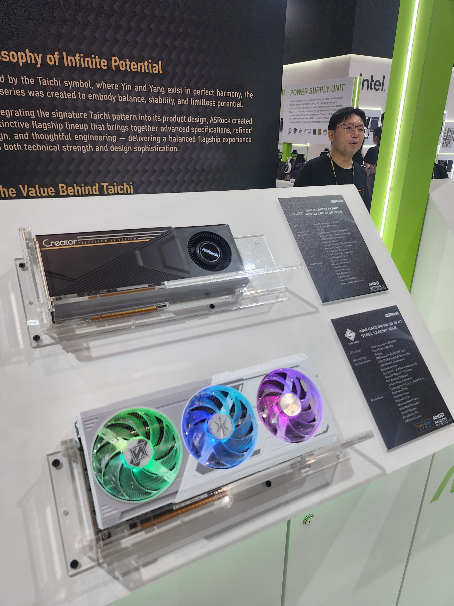 An ASRock graphics card display featuring the 'Creator' and the 'AMD Radeon RX 6750 XT Steel Legend 16GB' models, with colorful LED fans, is showcased beside an ASRock informational plaque in front of an 'Intel' sign.