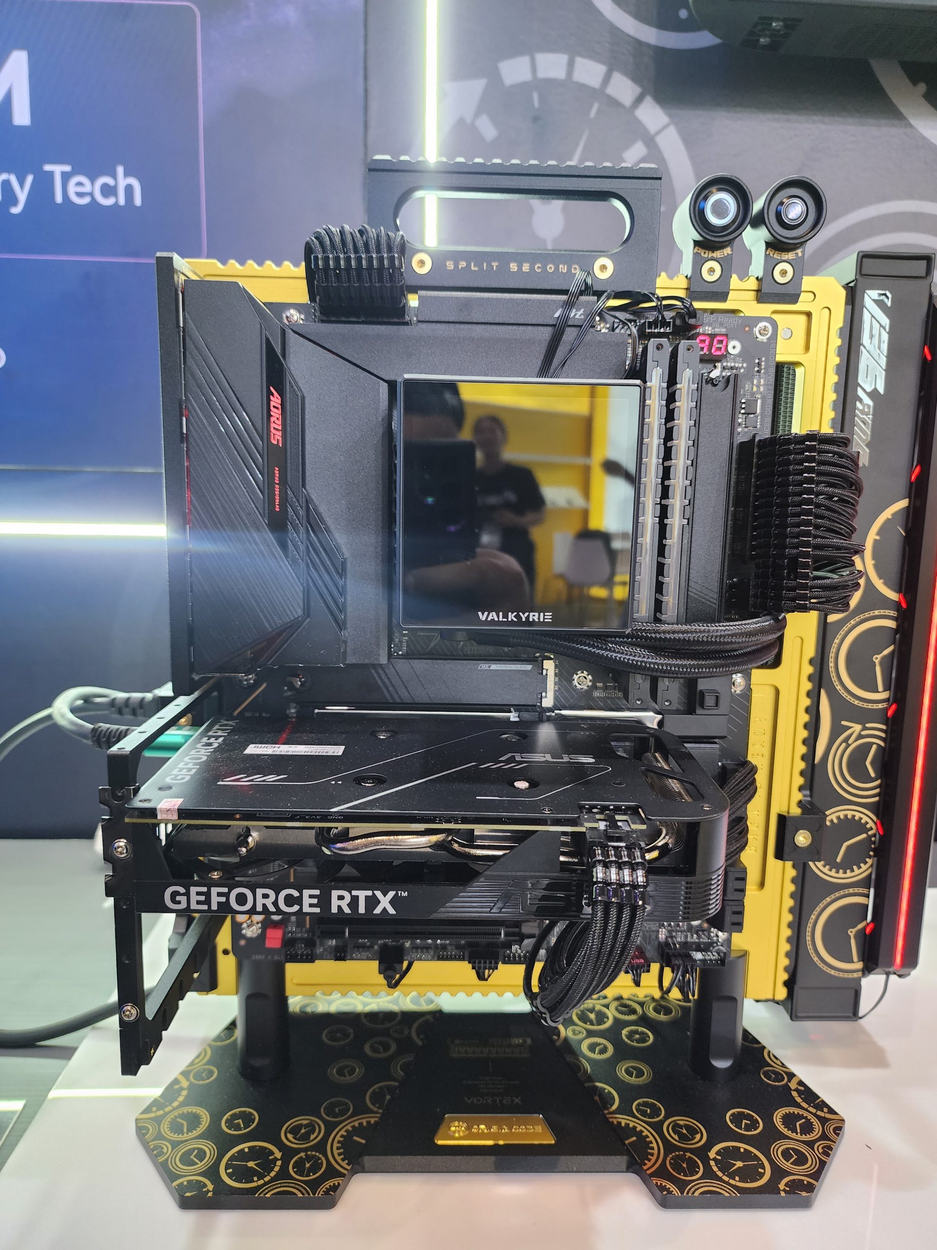 A custom PC build featuring an AORUS VALKYRIE motherboard, a GeForce RTX GPU, and visible 'SPLIT SECOND' branding, displayed on a decorative base with clock designs.