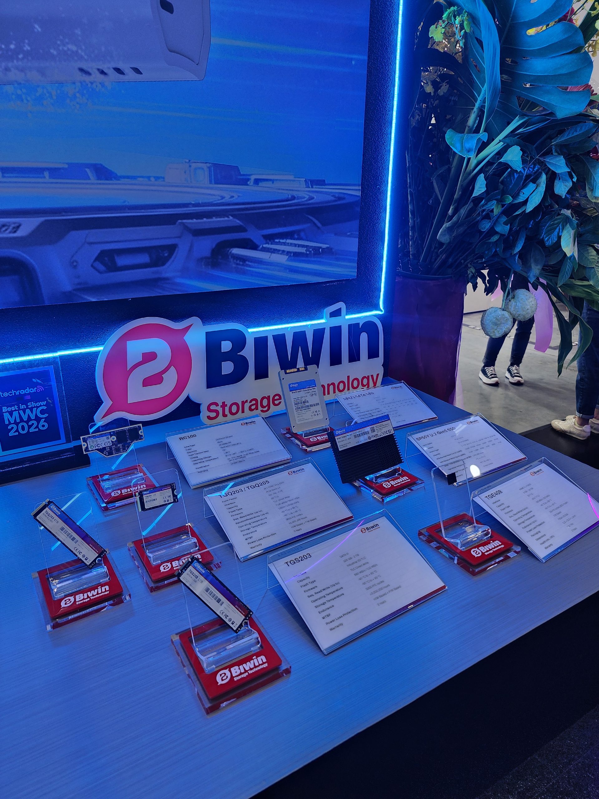 A display booth featuring multiple Biwin storage devices, each marked with individual labels, alongside a sign reading 'Best in Show MWC 2026'.