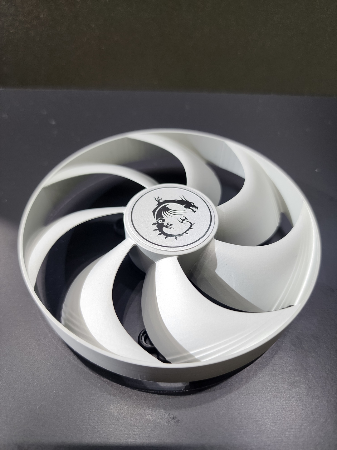 A cooling fan featuring the MSI dragon logo on its center, displayed on a dark surface.
