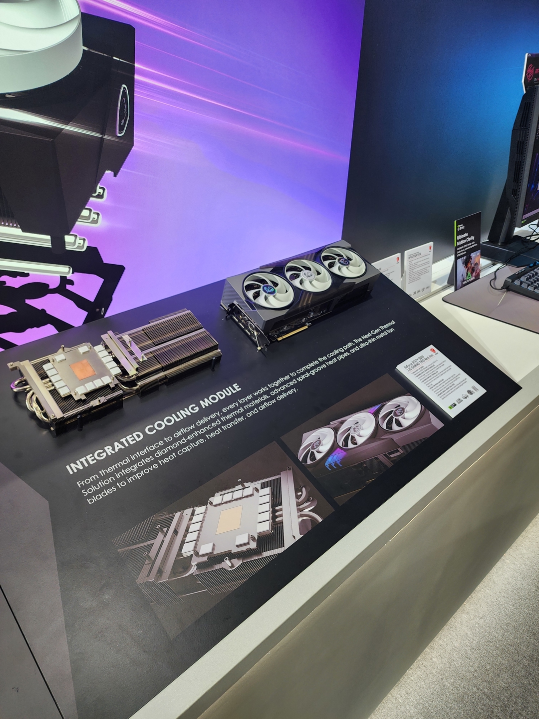 An AMD graphics card display showcases an integrated cooling module with three fans alongside informative graphics and text about its heat management features.
