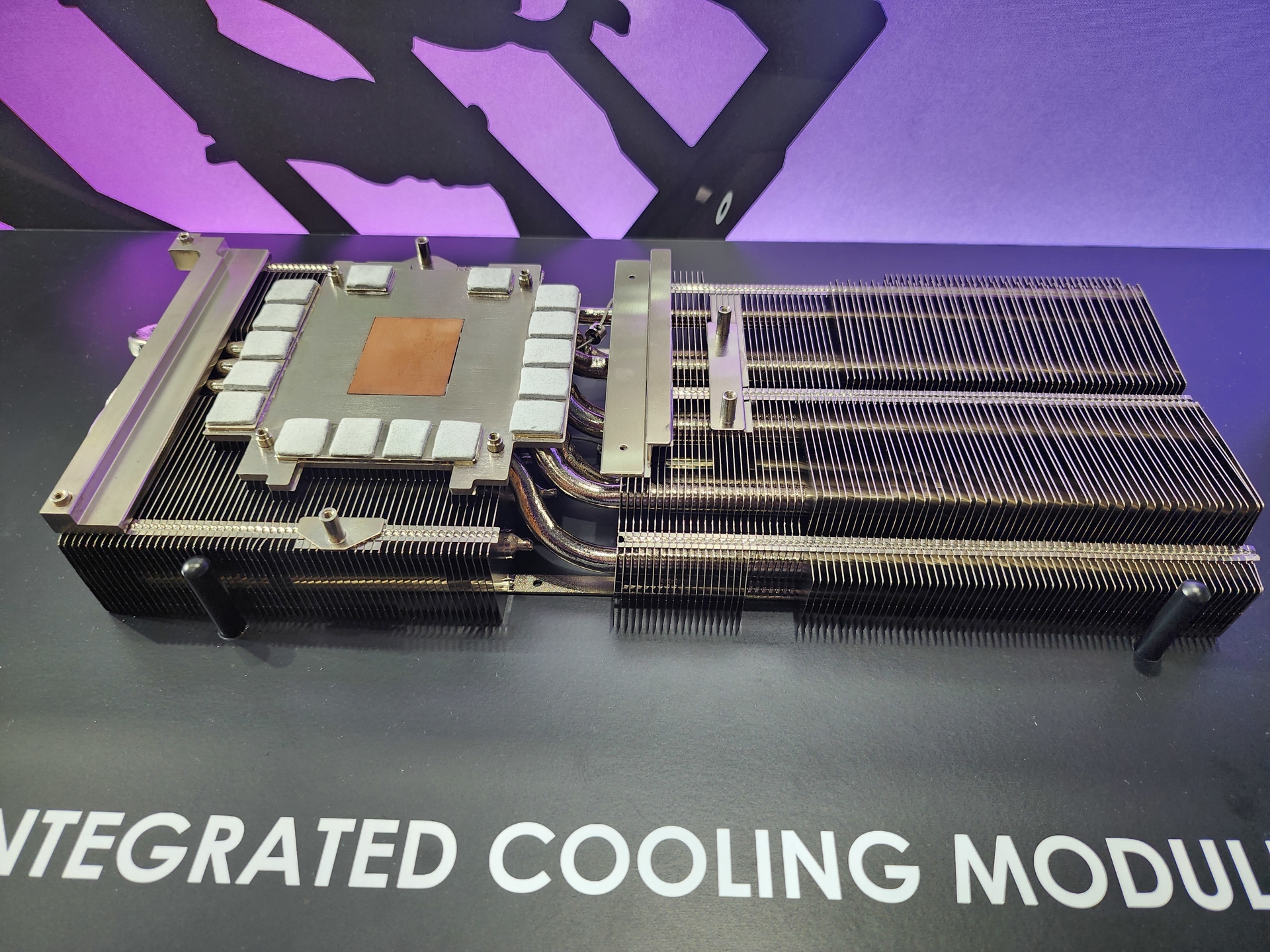 A close-up of an unbranded cooling module with visible heat pipes and fins on a surface labeled 'INTEGRATED COOLING MODULE'.