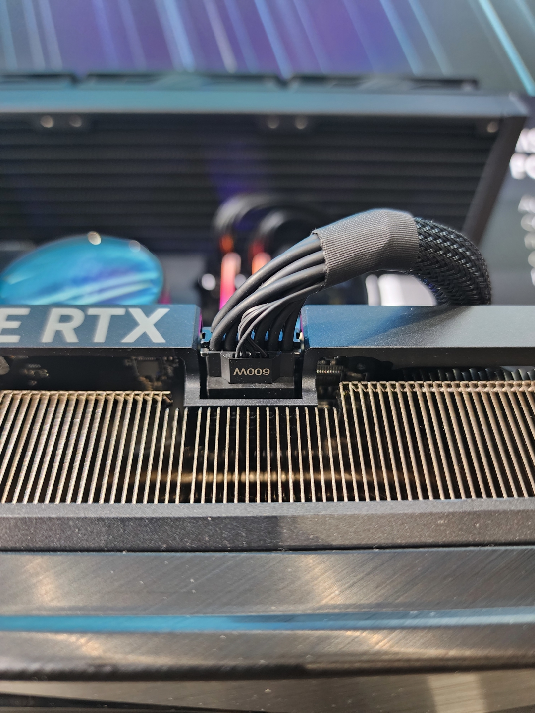 A close-up of an NVIDIA GeForce RTX graphics card shows a 600W power connector attached.