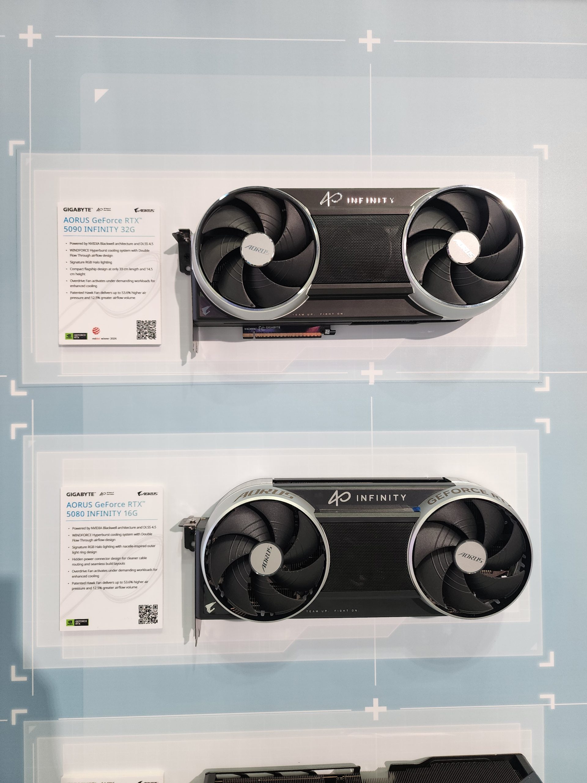 Two GIGABYTE AORUS GeForce RTX graphics cards are displayed, labeled as 'AORUS GeForce RTX 5090 INFINITY 32G' and 'AORUS GeForce RTX 5080 INFINITY 16G,' each with dual fans and a visible information card.