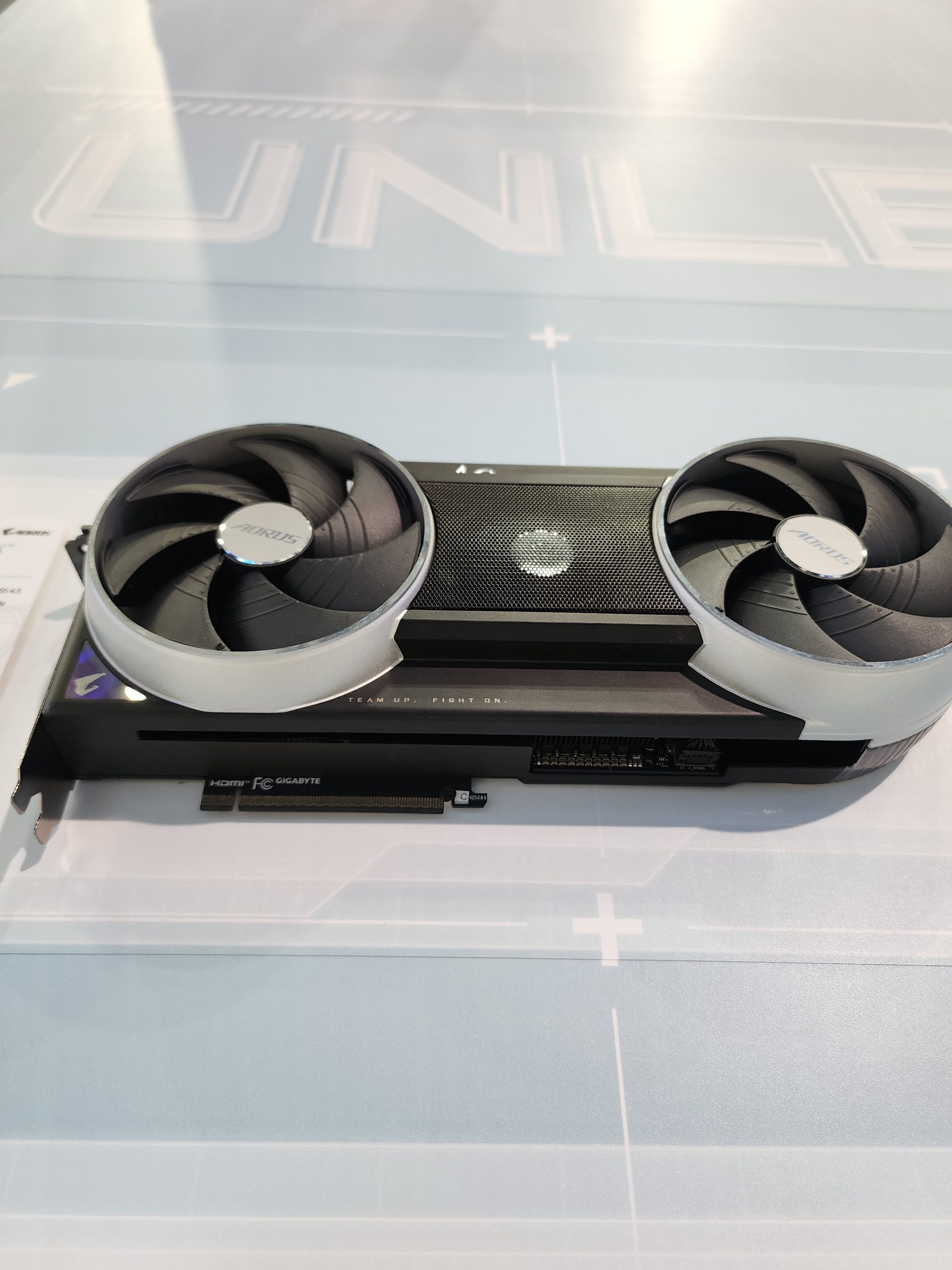 Gigabyte Aorus graphics card with dual fans and visible text 'TEAM UP. FIGHT ON.' displayed on a table.