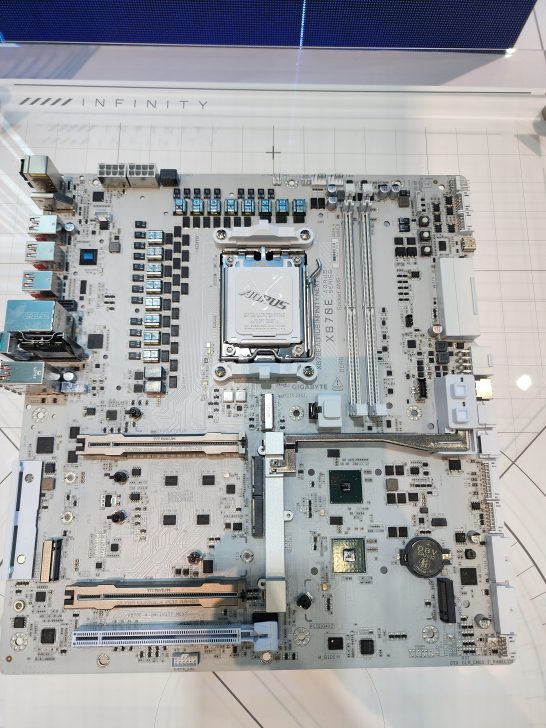 A Gigabyte X87E motherboard featuring multiple PCIe slots, USB ports, and visible 'Aorus' branding on the CPU socket.